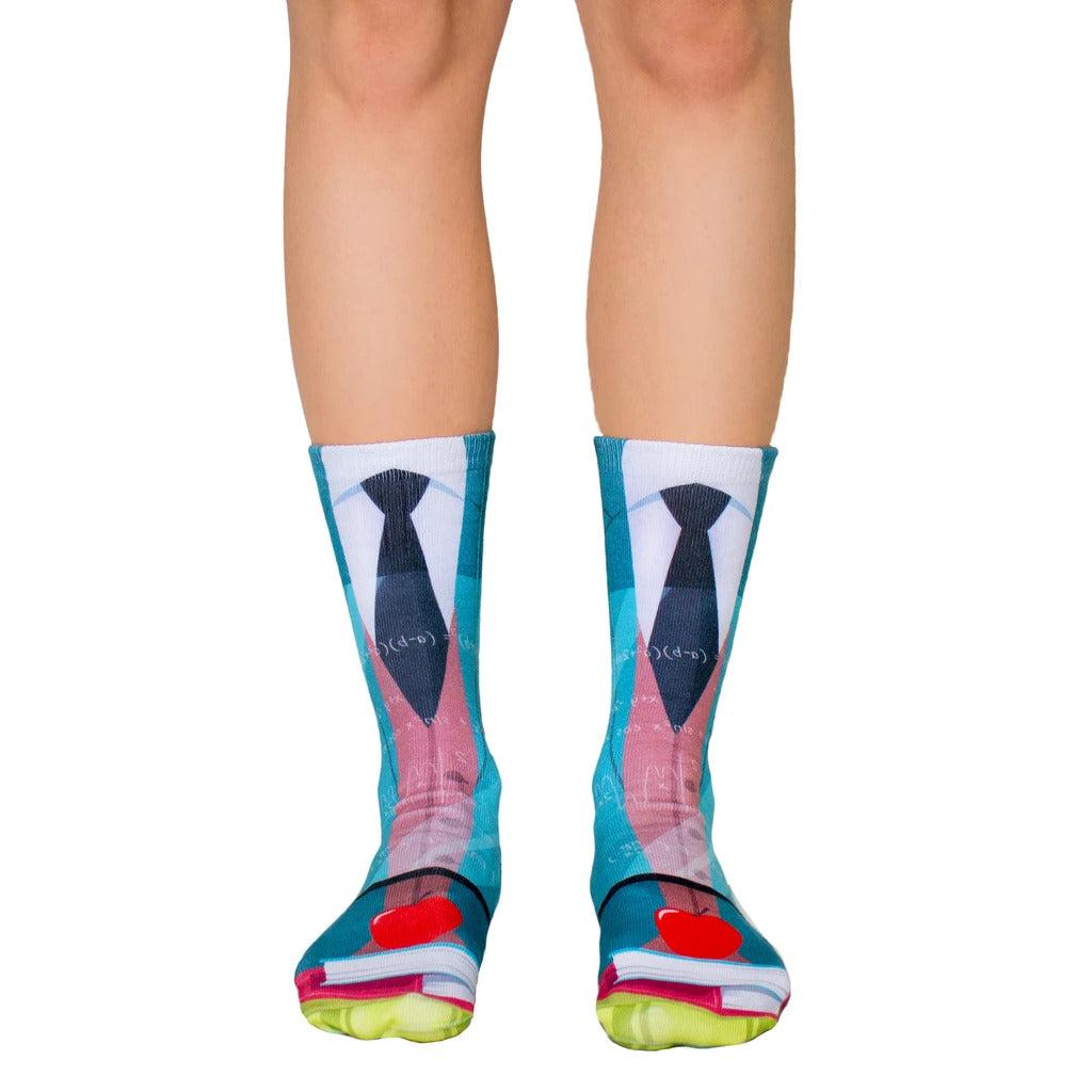 A pair of crew socks with a teacher-themed design: teal, blue, and red, showing a tie, books, and an apple. [lf]