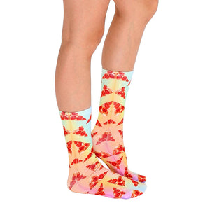 A pair of legs is shown from the knees down. The person is wearing rainbow tie-die socks with a pattern of pizza slices.