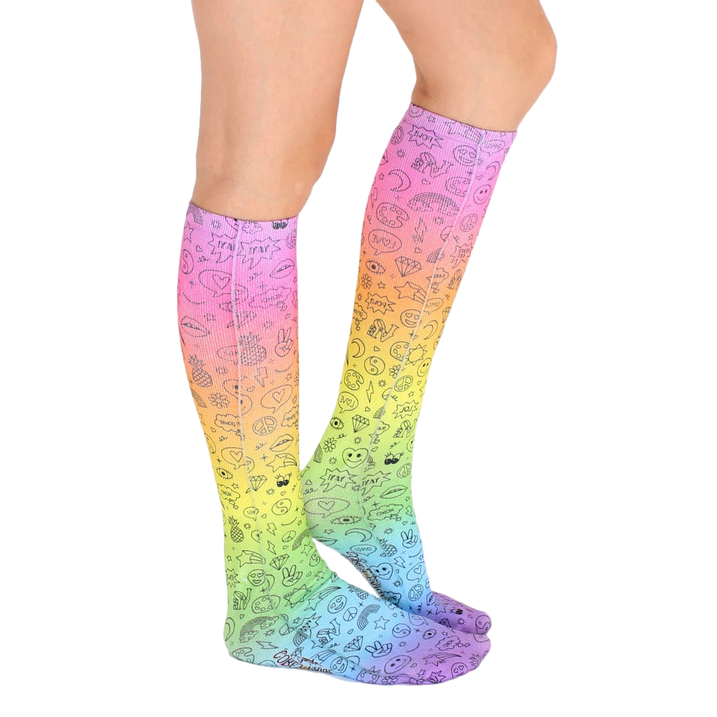 Lifestyle photo showing a person's legs wearing the rainbow doodle knee-high socks. [lf]