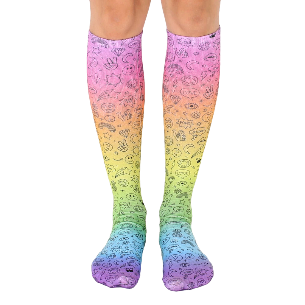 Pair of rainbow gradient knee-high socks with black doodle icons including peace signs, smiley faces, and other fun designs. [lf]