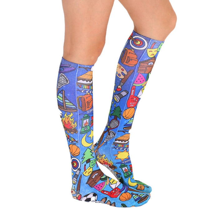 A pair of blue knee-high socks with a pattern of camping-related items such as tents, campfires, and hiking boots.