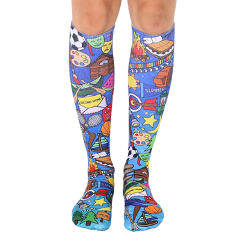 A pair of knee-high socks on a model's legs.  The socks are blue with colorful illustrations of summer camp activities, including sports equipment, campfires, and s'mores. [lf]
