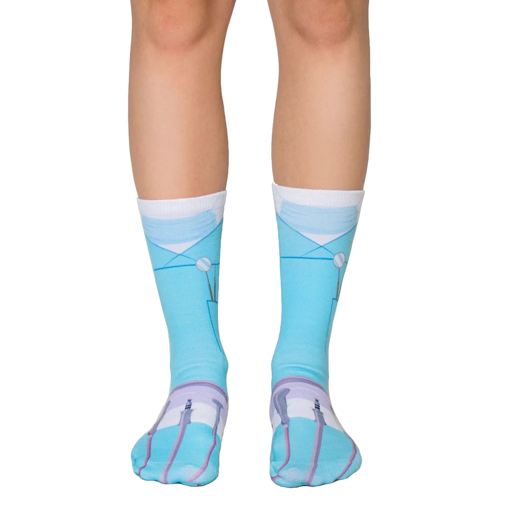 A pair of crew socks in light blue, depicting a dentist's scrubs with dental tools. The socks are shown on a model's legs. [lf]