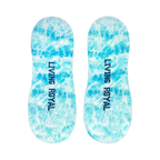 Flat lay image showcasing a pair of light blue no-show socks with a tie-dye effect and the words 'LIVING ROYAL' on them.