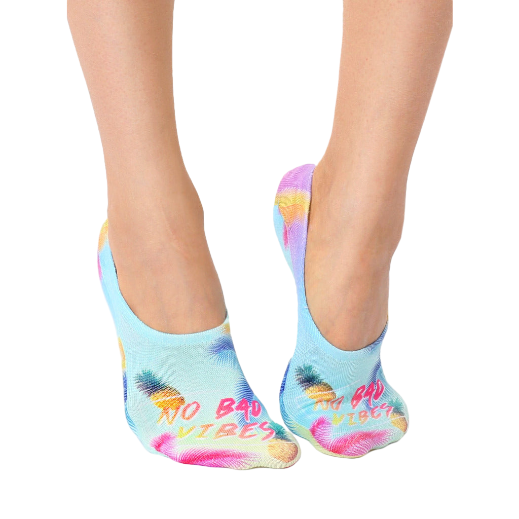 Lifestyle shot of a woman's feet wearing the 'No Bad Vibes' no-show socks. The socks are visible from the ankles down. [lf]