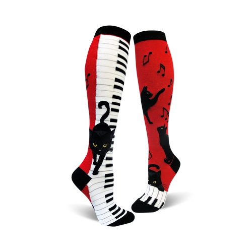 A pair of red and white knee-high socks with a piano keyboard and playful black cats.  Musical notes are also featured.