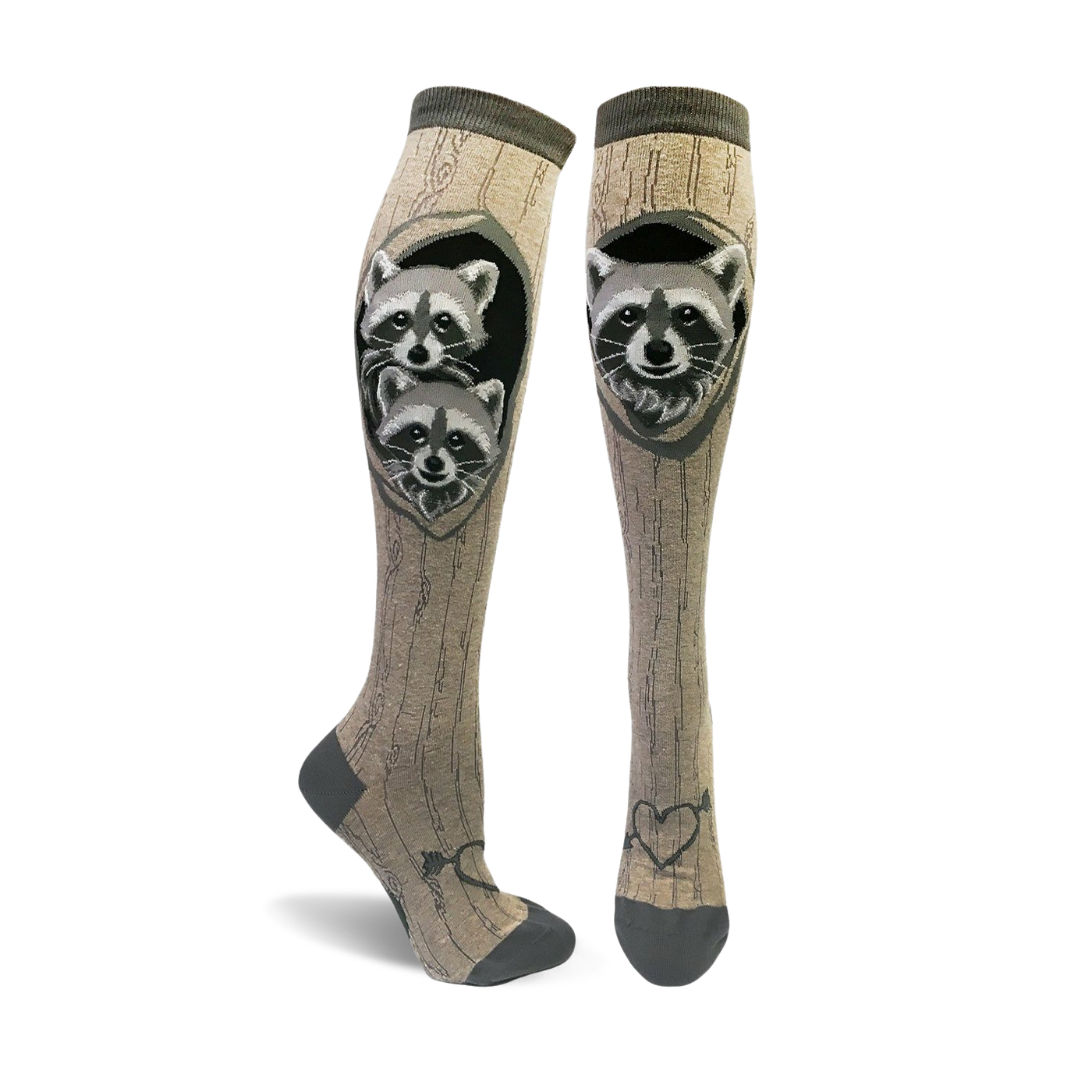 A pair of tan knee-high socks with a wood grain pattern and two raccoons peeking from a tree hole.  The socks have dark gray toes and heels, and a small heart with arrow detail at the ankle.