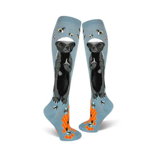 Pair of light blue knee-high socks with a honey badger giving the middle finger, bees, and honeycomb design.