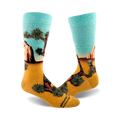 A pair of crew socks showcasing a Joshua Tree National Park landscape. The socks are teal and gold, depicting a desert scene with a prominent Joshua tree.
