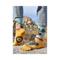 Lifestyle photo showcasing a person wearing the Joshua Tree socks. Their feet are placed on a rock in what looks like Joshua Tree National Park.