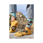 Lifestyle photo showcasing a person wearing the Joshua Tree socks. Their feet are placed on a rock in what looks like Joshua Tree National Park.