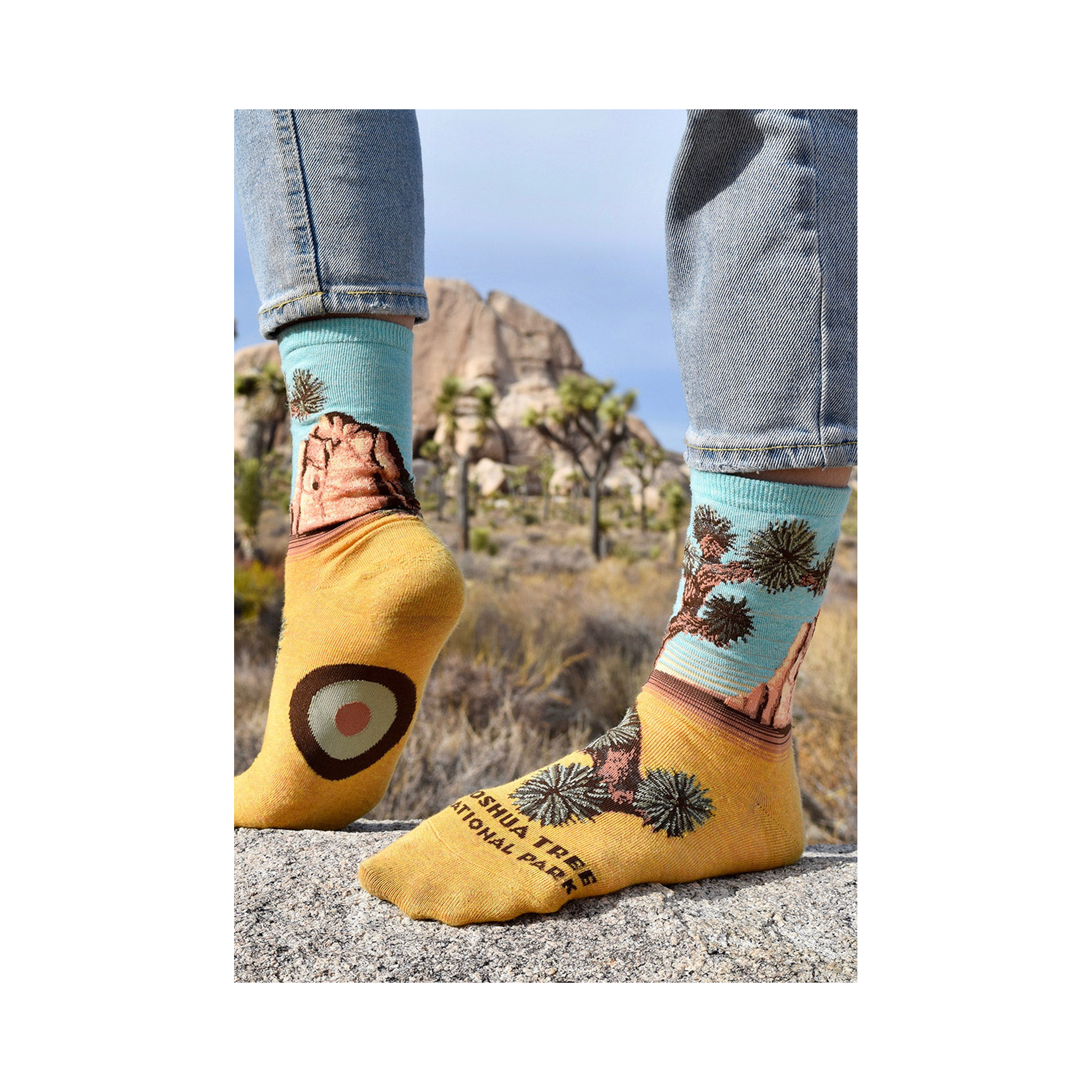 Lifestyle photo showcasing a person wearing the Joshua Tree socks. Their feet are placed on a rock in what looks like Joshua Tree National Park.