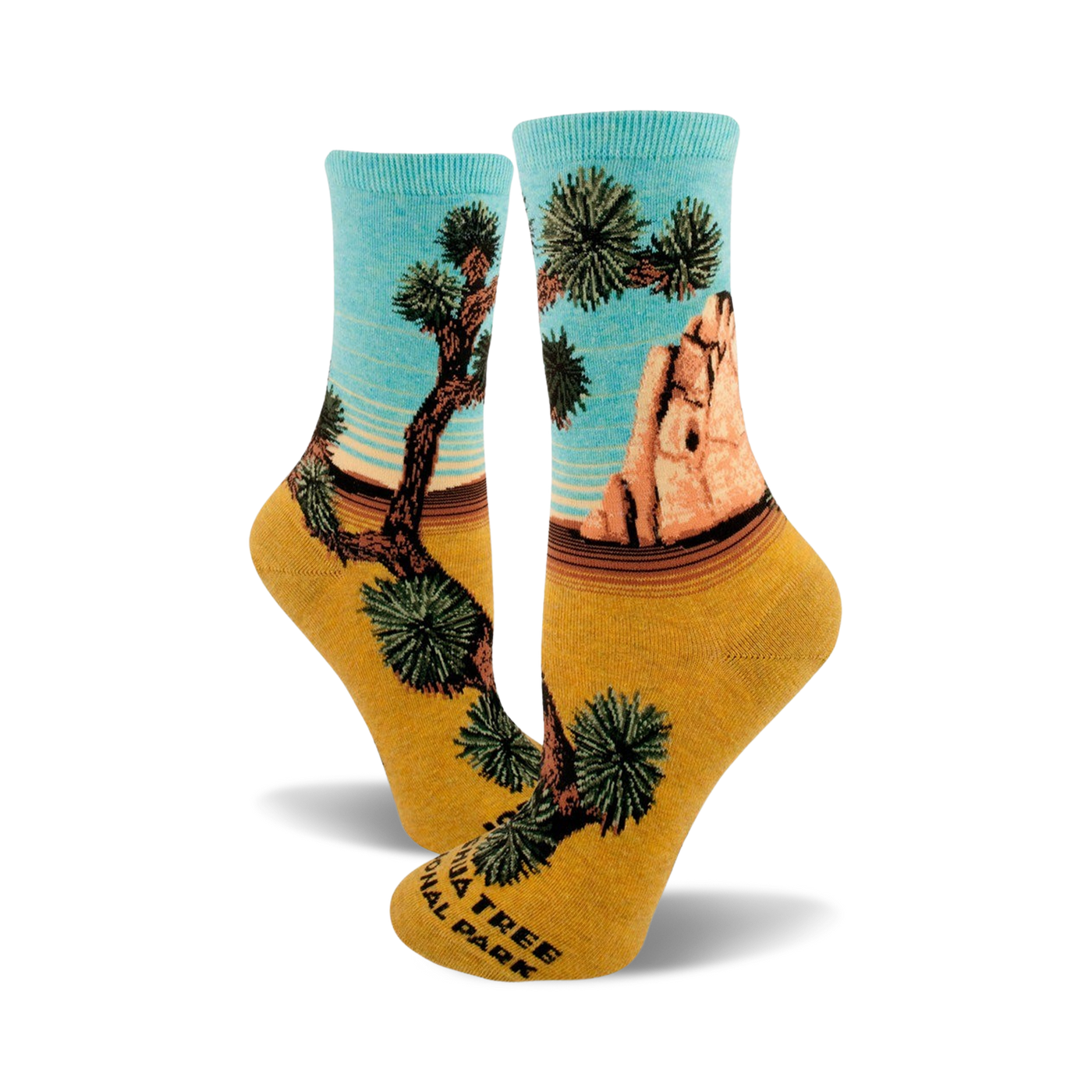 A pair of women's crew socks showcasing a Joshua Tree National Park design. The socks are teal and mustard yellow, depicting a desert landscape with iconic Joshua trees and rock formations.