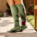 Lifestyle shot of a woman sitting on a wooden bench wearing the beet socks. [lf]