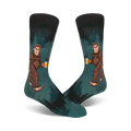 Pair of teal crew socks depicting a Bigfoot character enjoying a beer in a forest setting. Darker teal and black accents.