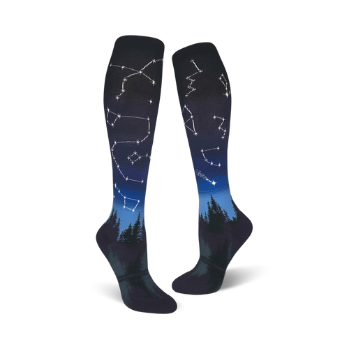 Pair of dark blue and black knee-high socks with constellations and a forest silhouette design.