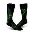 A pair of black crew socks featuring bright green fern and fiddlehead designs. Botanical illustration on a comfortable, everyday sock.