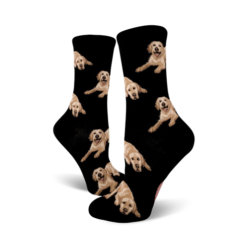 Pair of black crew socks covered in images of golden retrievers. The dogs are light tan and the background is black.
