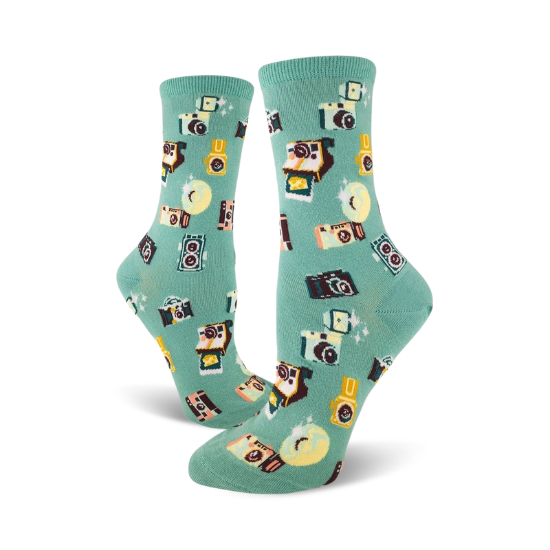 A pair of teal crew socks adorned with a whimsical pattern of retro cameras, film canisters, and sparkling details.