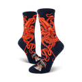 A pair of women's crew socks in navy blue, adorned with a striking orange squid design.  The squid's tentacles wrap around a small grey whale illustration at the bottom.