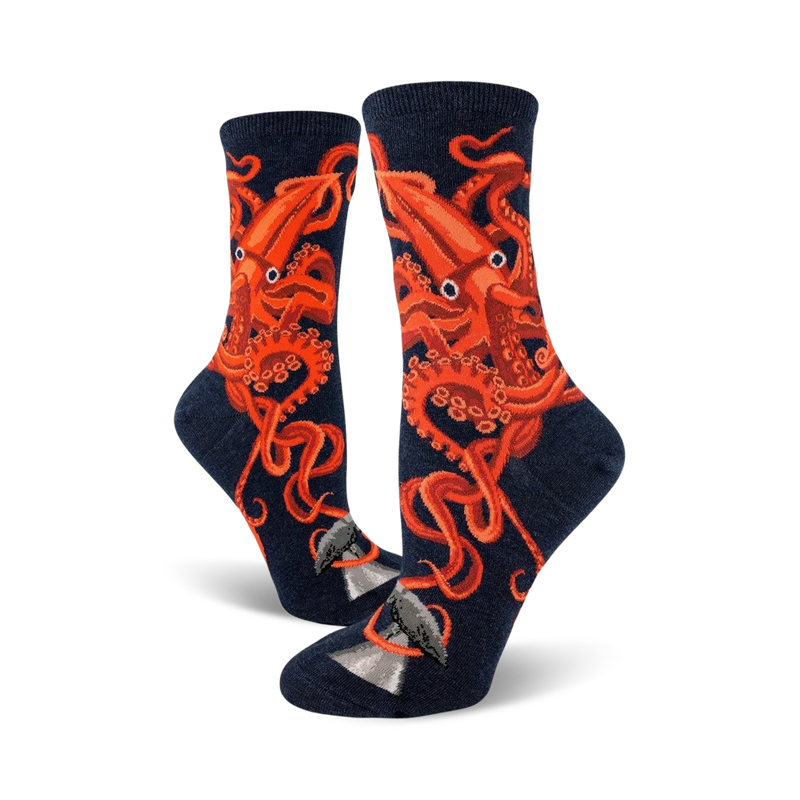 A pair of women's crew socks in navy blue, adorned with a striking orange squid design.  The squid's tentacles wrap around a small grey whale illustration at the bottom.