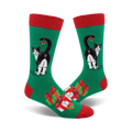 A pair of crew socks. Green background with a black and white cat with mistletoe, plus presents. Red and green accents.