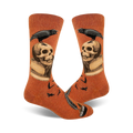 Pair of burnt orange crew socks.  A black raven perches on a skull resting on an open book, with a quill pen at the bottom.  Small ravens also in the background.