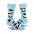 Crew socks in light blue with snowflakes.  Design features dachshunds wearing red and green capes flying across a snowy background.
