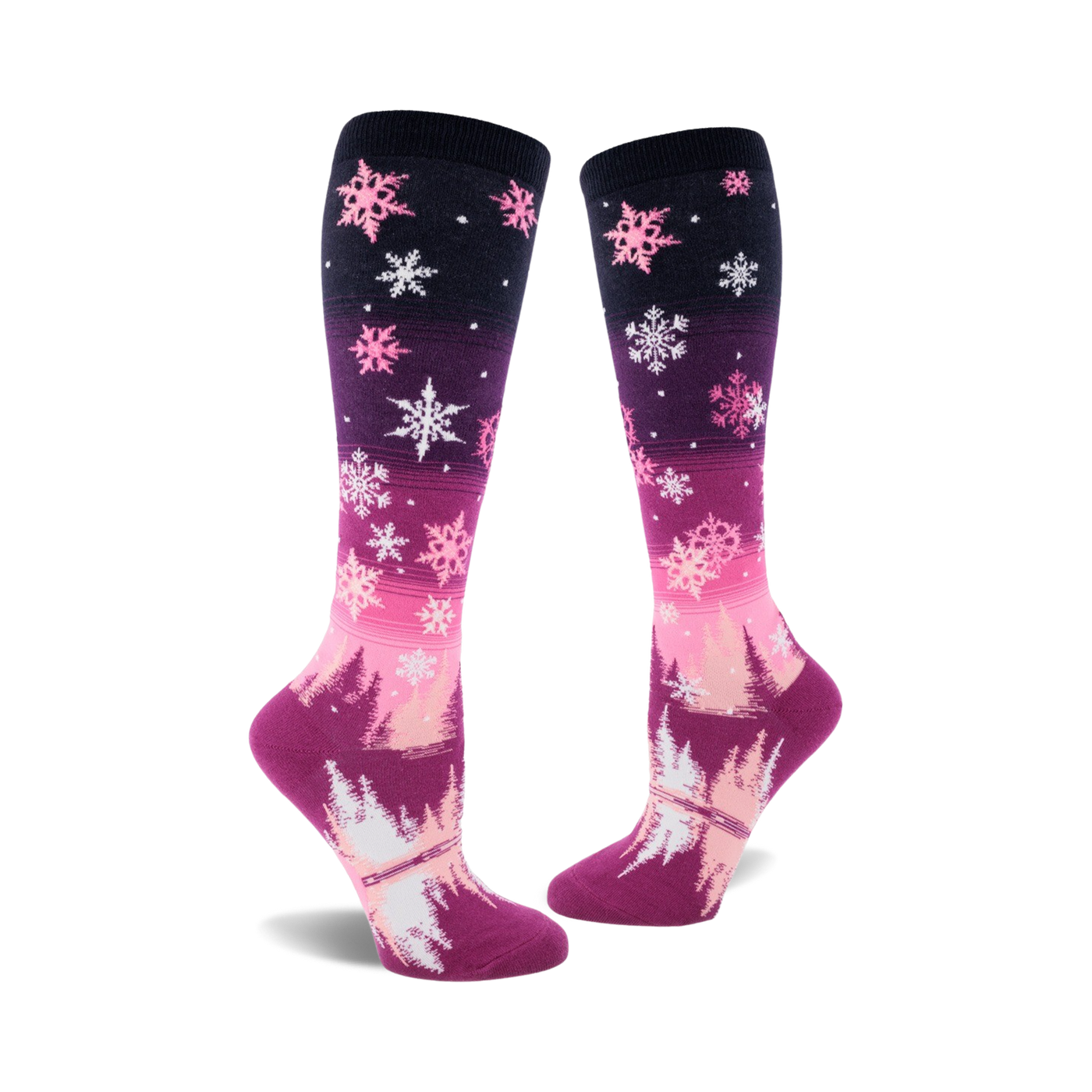 Pair of women's knee-high socks. Pink and purple ombre design with white snowflakes and a winter forest scene at the bottom.