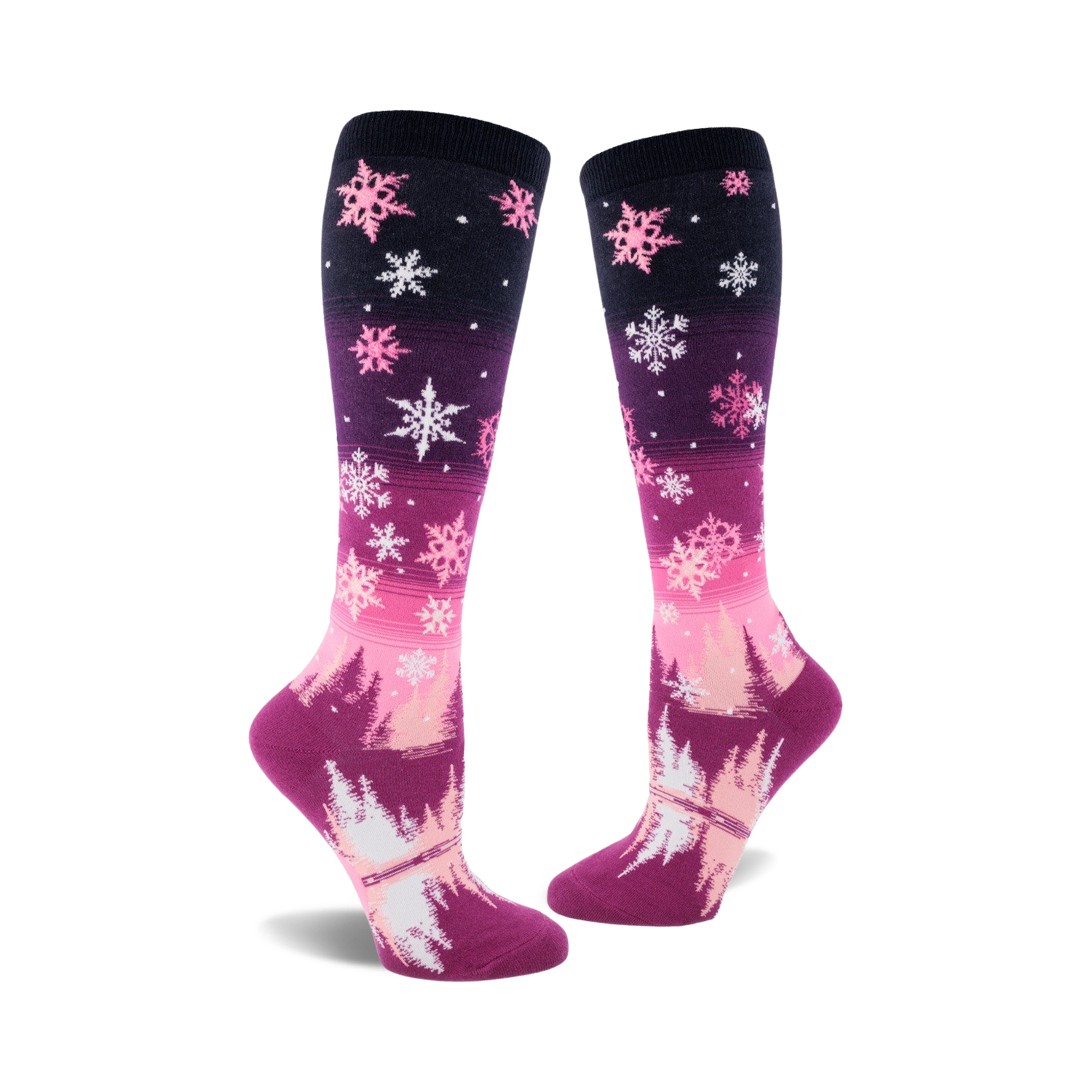 Pair of women's knee-high socks. Pink and purple ombre design with white snowflakes and a winter forest scene at the bottom.