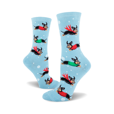 pair of women's crew socks, sky blue background, featuring dachshunds in winter sweaters and scarves leaping through snowflakes.  front view.