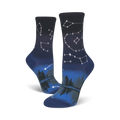 Pair of crew socks in navy blue and dark grey. Features a night sky design with constellations and a forest reflection.