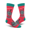A pair of coral crew socks with a teal cuff. The socks feature a black and white hypnotic bicycle design and the words 'Cycle Therapy' and 'Committed'.