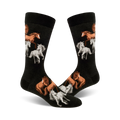 A pair of black crew socks with a pattern of brown and white horses. The horses are depicted in a playful, slightly whimsical style.
