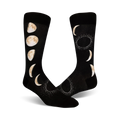 Pair of black crew socks with a beige moon phase design.  The socks feature crescent moons and full moons, with subtle sparkle detailing.