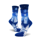Pair of blue crew socks with a snowflake and pine tree design.  The socks are predominantly blue with white snowflakes and stylized trees.