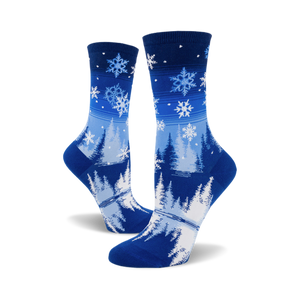 Pair of blue crew socks with a snowflake and pine tree design.  The socks are predominantly blue with white snowflakes and stylized trees.