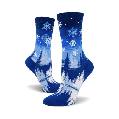 pair of women's crew socks; front view. blue snowflake design on a dark-to-light blue gradient background.  bottom features snowy pines and a lake.