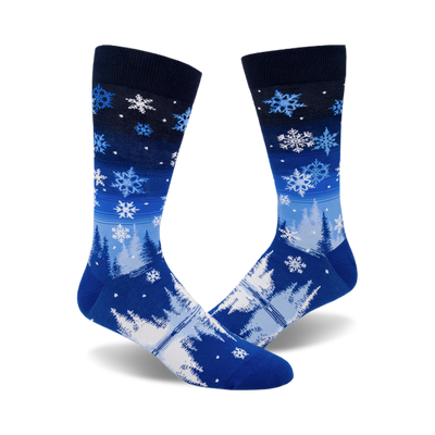 pair of men's crew socks; front view. blue snowflake design on a dark-to-light blue gradient background.  bottom features snowy pines and a lake.