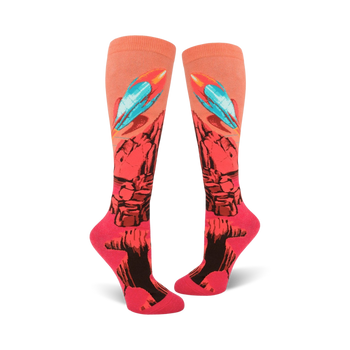 bright pink knee high women's socks feature a pattern of rockets blasting off from a red planet with blue flames. 