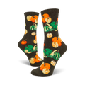 A pair of women's crew socks in dark green, adorned with a whimsical pattern of orange and green pumpkins and gourds.