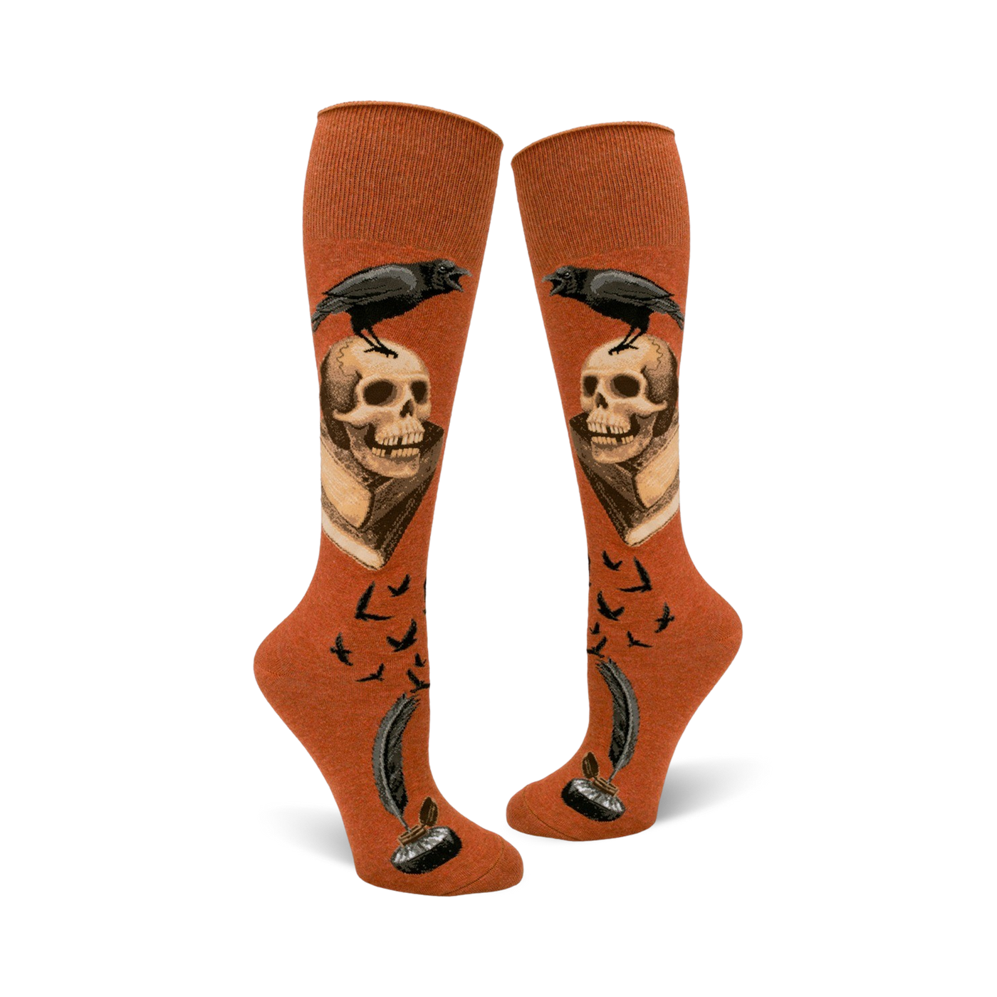 Pair of rust-colored knee-high socks. Design includes a raven perched on a skull above an antique book, quill pen, inkwell, and flying birds.