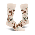 A pair of cream-colored crew socks adorned with a pattern of brown pinecones and green pine branches. The design is a whimsical, nature-inspired motif.