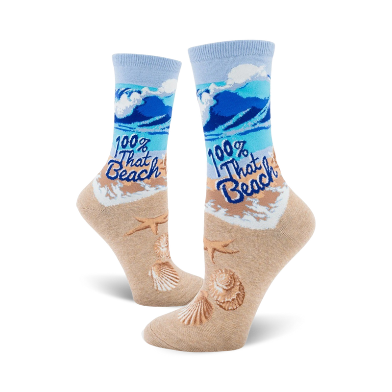 A pair of women's crew socks showcasing a beach scene with blue waves, tan sand, seashells, starfish, and the text '100% That Beach'.