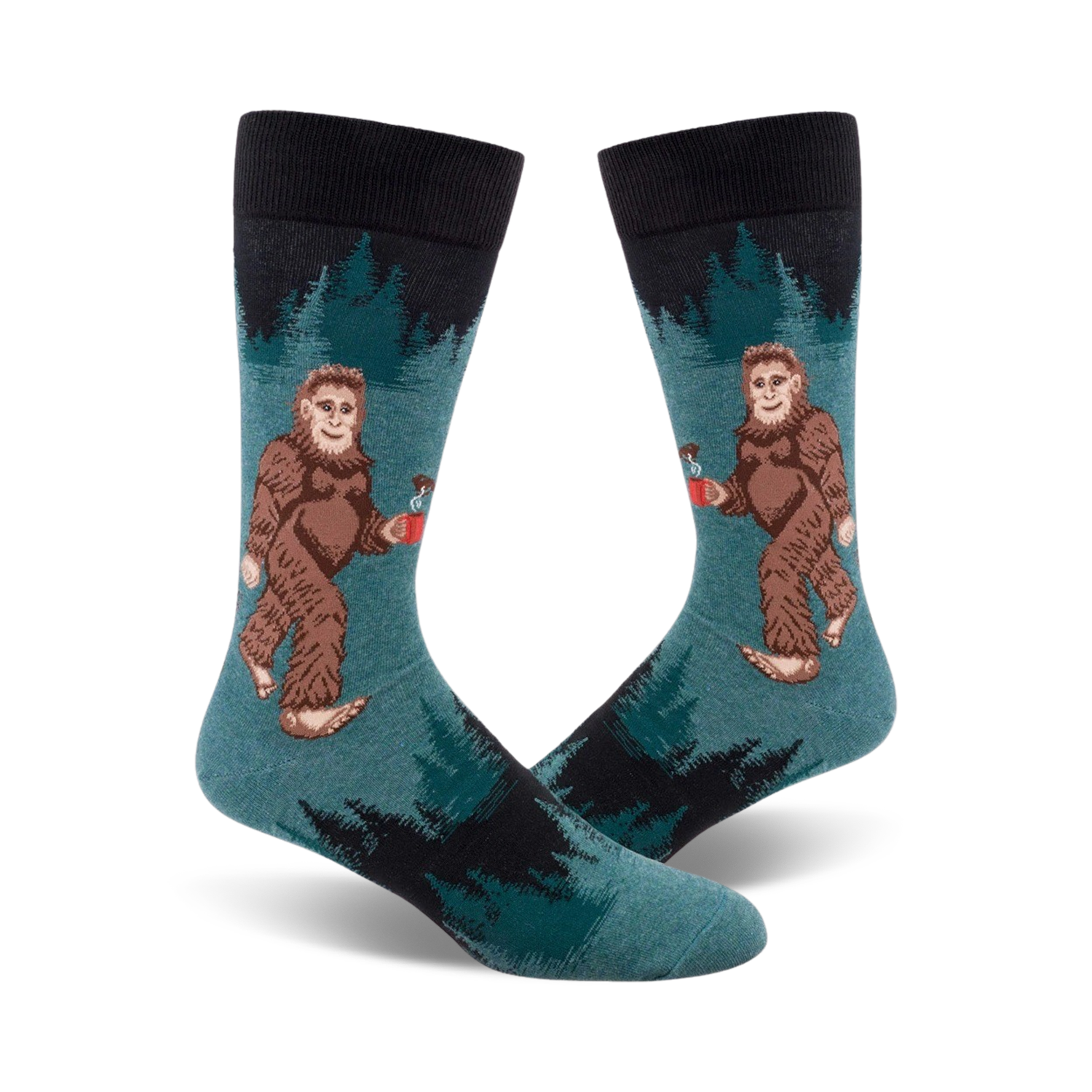 A pair of teal crew socks with a Bigfoot design holding a mug. Black sock top and dark green forest design in the background.
