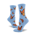 A pair of light blue crew socks adorned with a pattern of orange monarch butterflies. The socks are shown from the side, one sock partially obscuring the other.