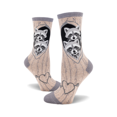 side view of two crew socks with raccoons peeking out of a tree trunk. the socks have hearts and an arrow on the bottom.