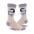 A pair of beige crew socks with a grey cuff.  The design shows two raccoons peeking out of a tree trunk hole.