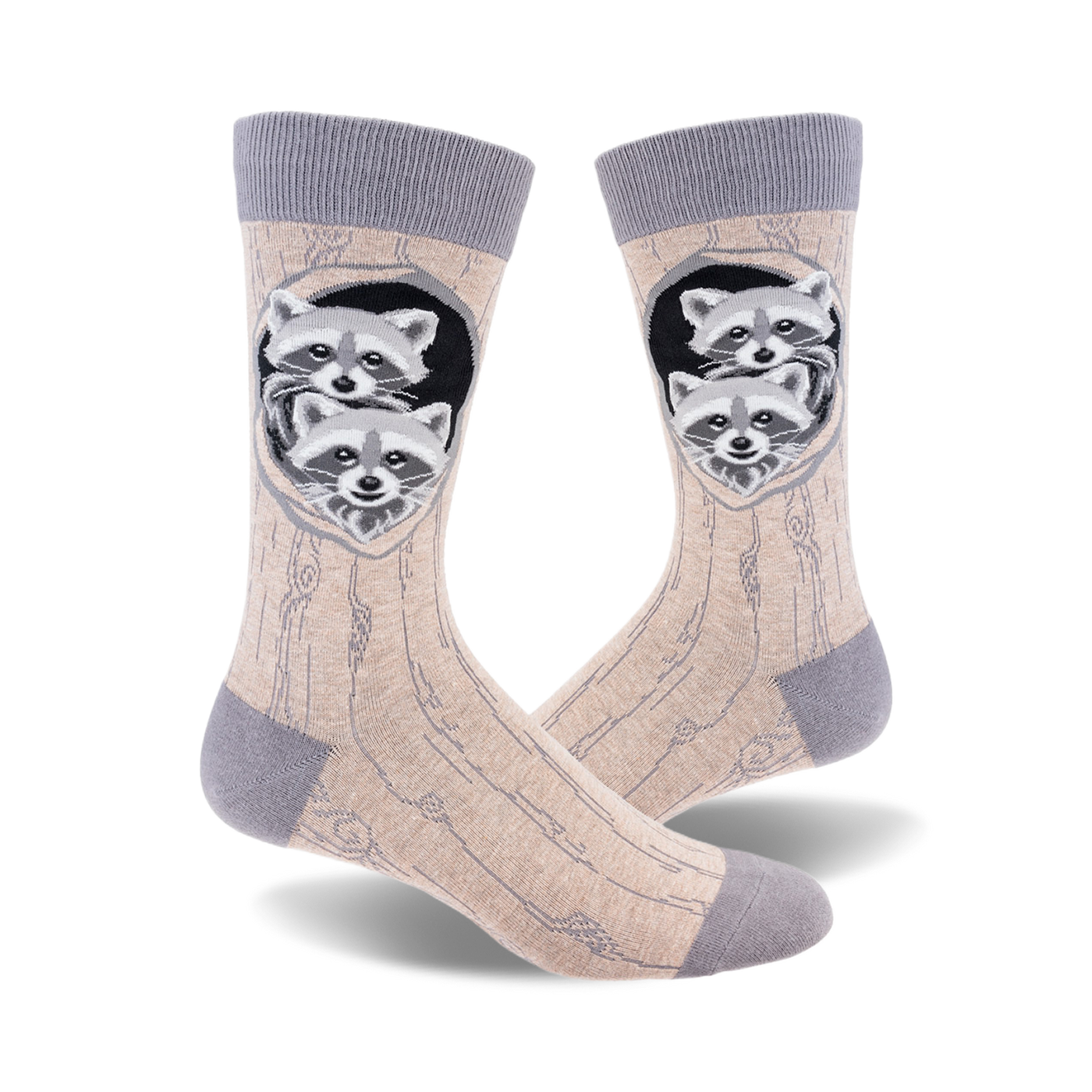 A pair of beige crew socks with a grey cuff.  The design shows two raccoons peeking out of a tree trunk hole.