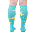 Rear view of model wearing teal Bananarwhal knee-high socks; showing the full sock design.